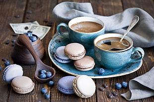 two blue teacups with cakes, coffee, macaroons, blueberries