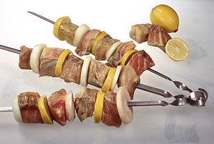 beef and lemon slice with skewer on top of white surface