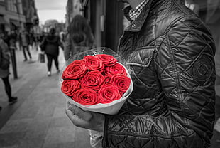 selective color photo of man holding bouquet of rose near the street
