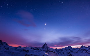 snow-covered mountain ranges under blue sky and clouds with stars