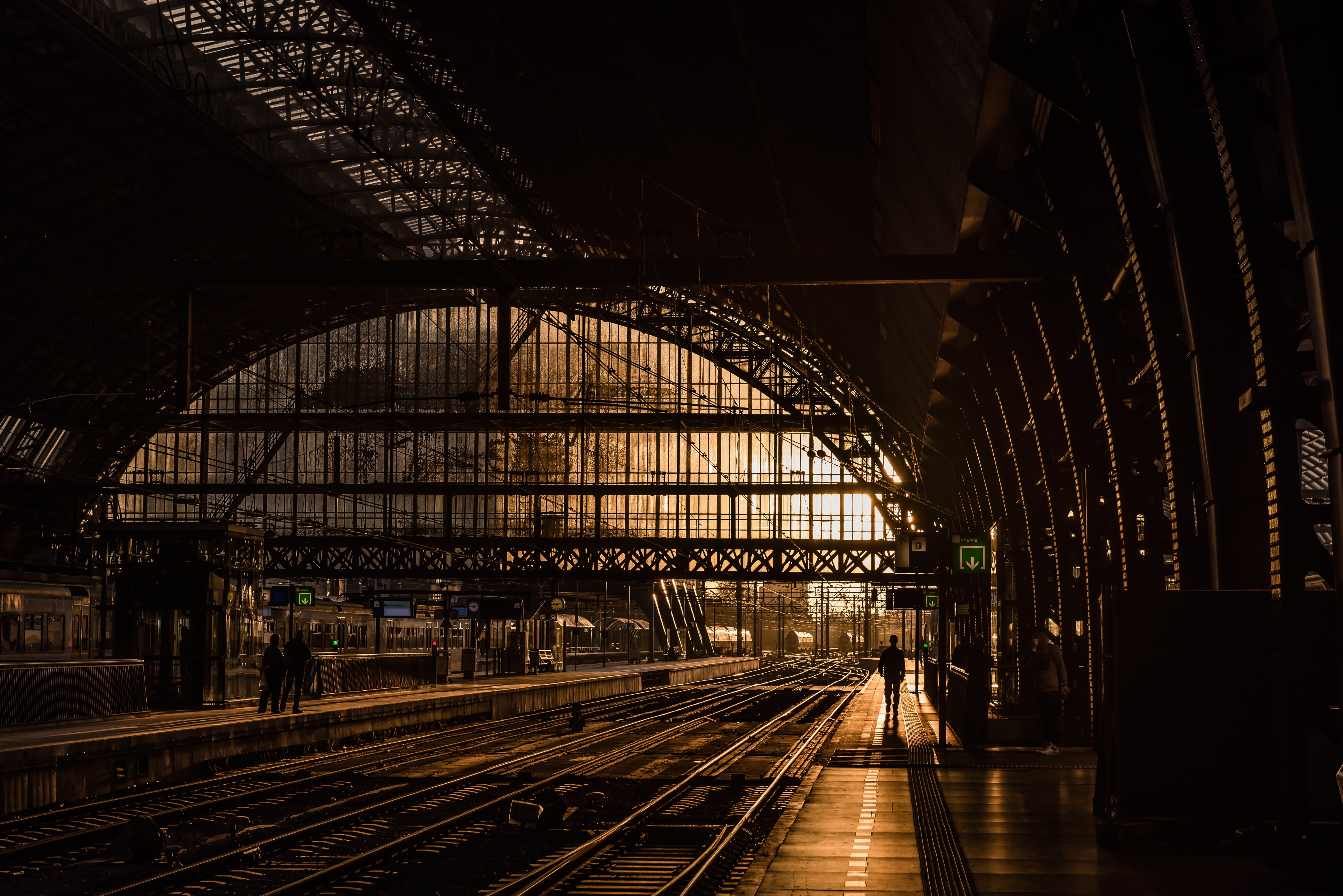 silhouette of person on train station near railroad during sunset