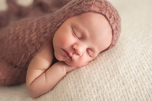 baby in brown knitted textile sleeping laying on white textile HD wallpaper