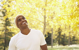 man wearing v-neck top looking at tree leaves