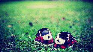 shallow focus photography of pair of black-and-red sneakers on green grass field during daytime HD wallpaper
