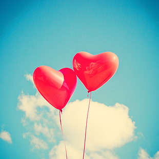two red heart-shaped balloons  during daytime