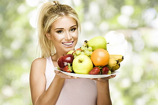 woman holding plate of assorted fruits