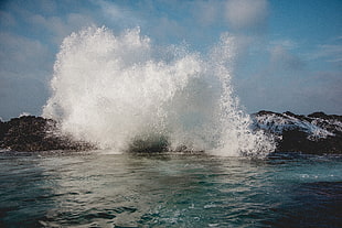 sea waves crashing on rock monolith