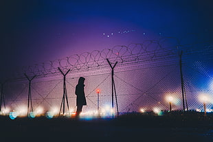 silhouette photo of person near fence