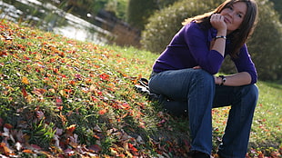 woman in purple long-sleeved shirt sitting on grass