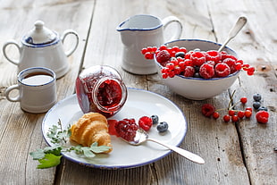 raspberry and blueberry jam with croissant on brown wooden surface