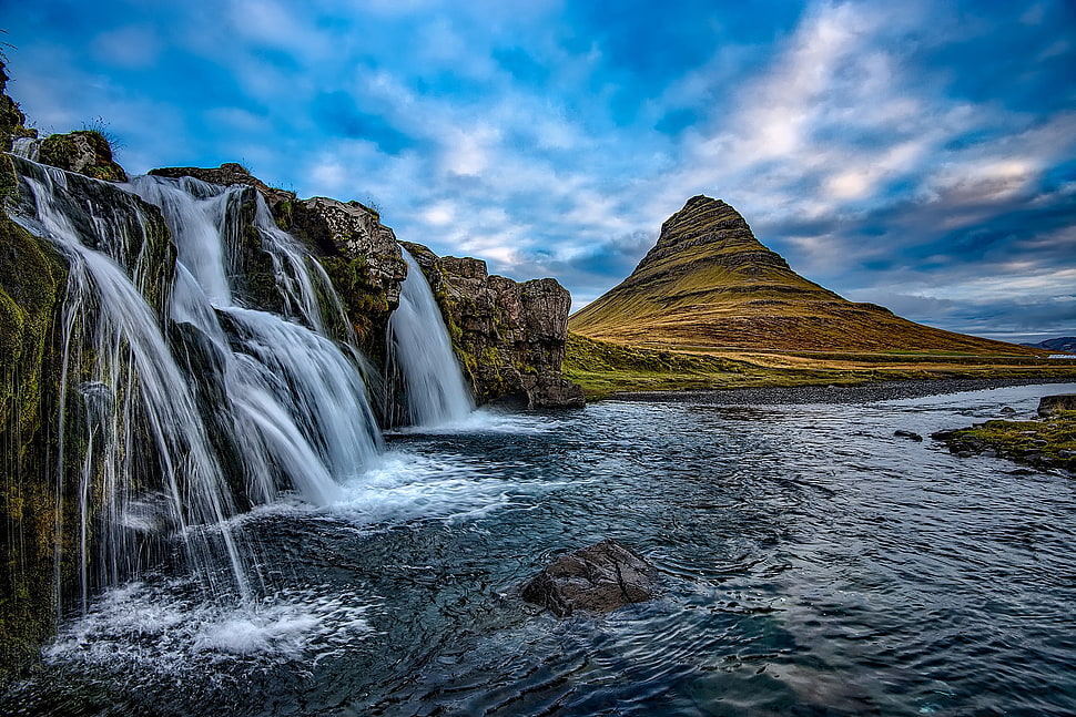 waterfalls near mountain range under cloudy sky HD wallpaper
