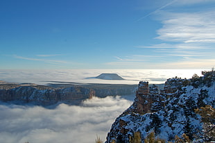 brown snow covered mountain surrounded by sea of clouds during daytime, grand canyon national park