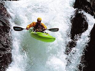 man wearing yellow and black jacket kayaking on running water