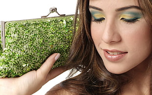 closeup photo of woman holding green beaded kisslock clutch bag