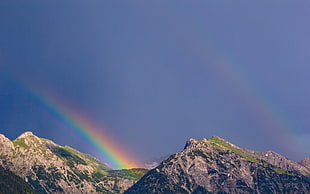 photo of two rainbow overlapsing mountain ridge