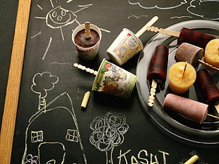 assorted ice cream on sticks with containers on black chalkboard