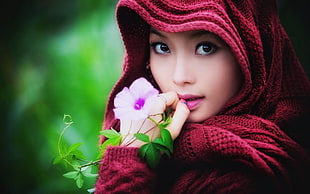 woman wearing red knitted headscarf near pink petaled flower