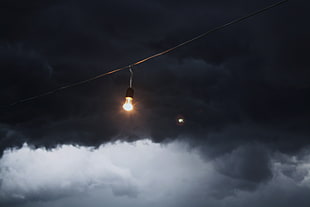 switched on light bulb under dark sky