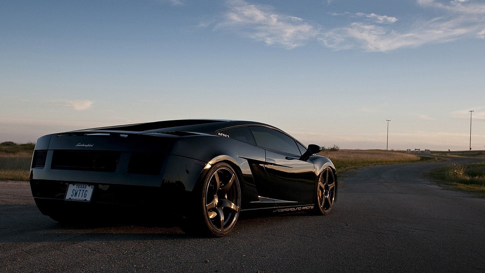 black Lamborghini coupe on pavement HD wallpaper