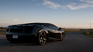 black Lamborghini coupe on pavement HD wallpaper