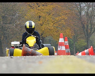 man wearing black and yellow full-face helmet while riding on black and yellow go-kart