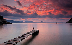 brown wooden dock and view of sea during golden hour