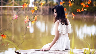 woman wearing white sleeveless top sitting near body of water HD wallpaper