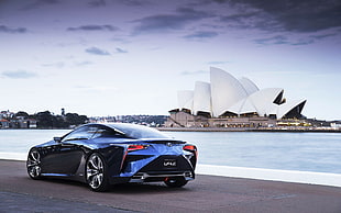 blue BMW sports coupe across Sidney opera house at daytime
