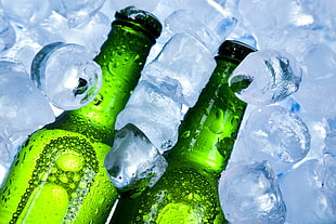 two green glass bottle with ice cubes