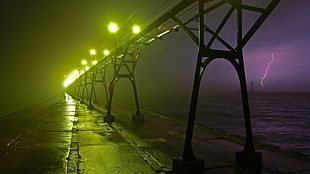 grey concrete bridge near body of water during nighttime