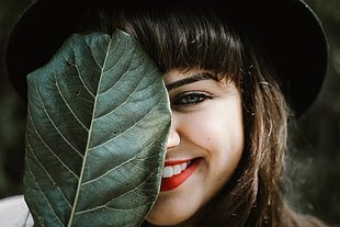 woman coveting her face with green leaf