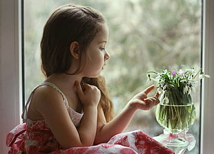 toddler girl touching white flowers in vase