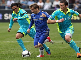 three soccer player on field during daytime