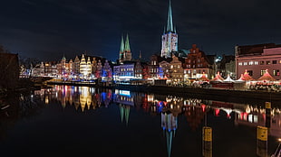 lightened city buildings near body of water during nighttime HD wallpaper