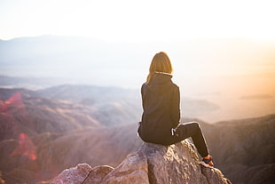 woman sitting on gray rock during daytime