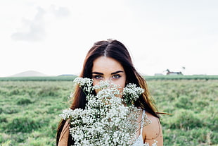 woman holding white Queen's Ann Lace flower during daytime HD wallpaper