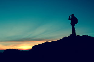panoramic photography of man standing on mountain during golden hour