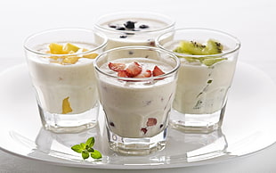 four glasses of fruit shakes on white ceramic palte