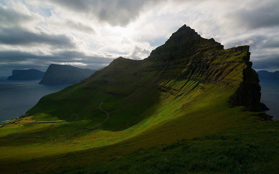 green grass field mountain during cloudy sky HD wallpaper