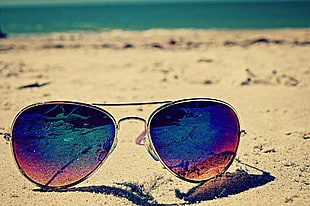 gold-colored framed aviator-style sunglasses on beach sand