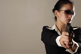woman wearing black blazer and white dress shirt holding pistol inside well-lit room