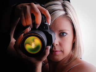 woman holding black DSLR camera