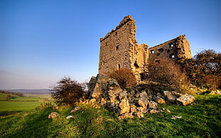 ruins of a concrete building on top of a hill under calm blue sky