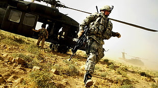 solider holding assault rifle walking in front of black helicopter