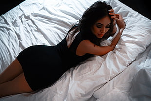 woman in black dress on top of white bed