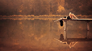 woman lying on wooden dock near body of water during daytime HD wallpaper