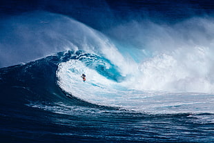 photo of person riding surf board in ocean wave