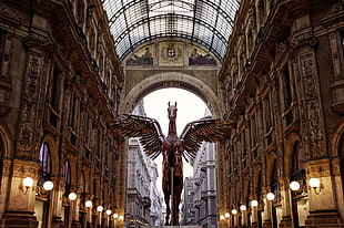 brown winged statue under architectural building