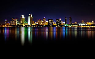 photography of high rise buildings beside body of water at nighttime HD wallpaper