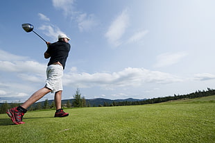 low angle photo of man in black shirt holding a golf club on grass field, trysil